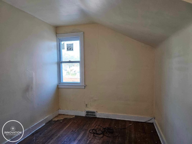 additional living space with dark wood-style flooring, visible vents, vaulted ceiling, and baseboards