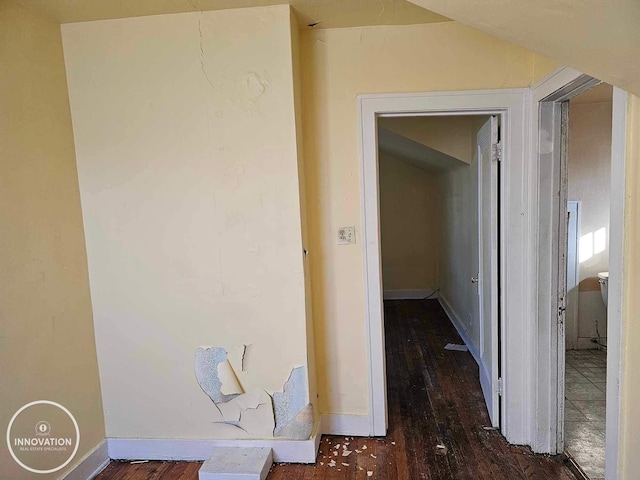 hall featuring dark wood-type flooring and baseboards