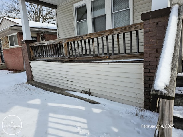 snow covered property with brick siding