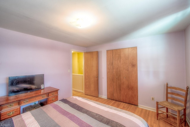 bedroom featuring light wood-type flooring, a closet, and baseboards