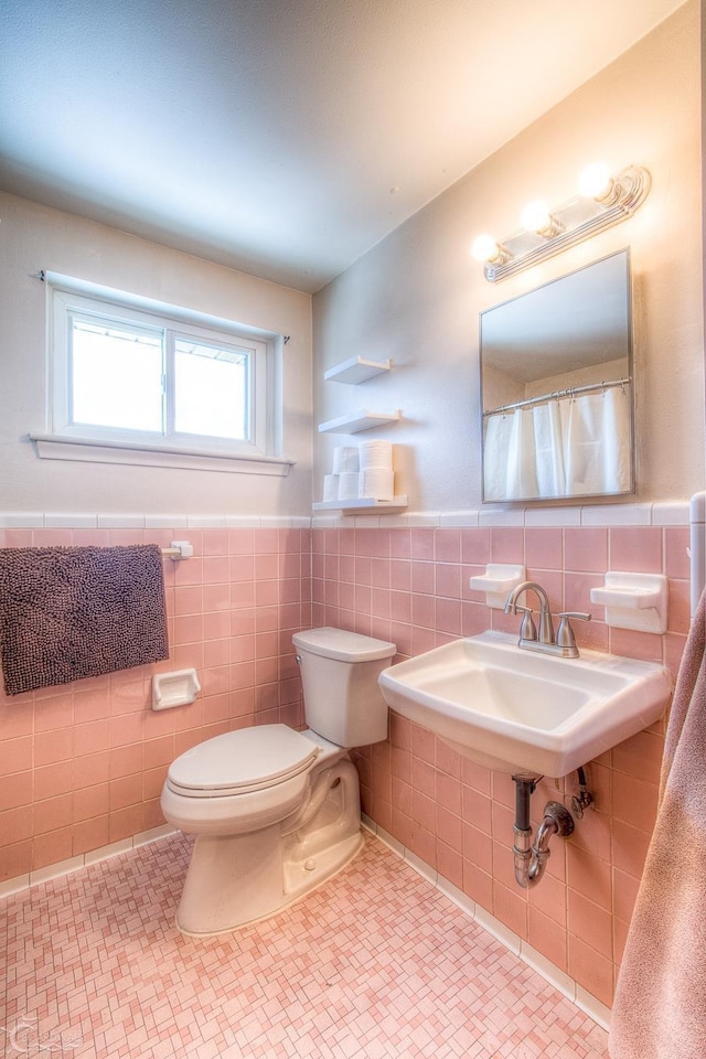 bathroom with toilet, a wainscoted wall, tile walls, and tile patterned floors