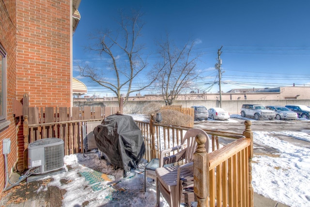 snow covered deck with area for grilling and central air condition unit