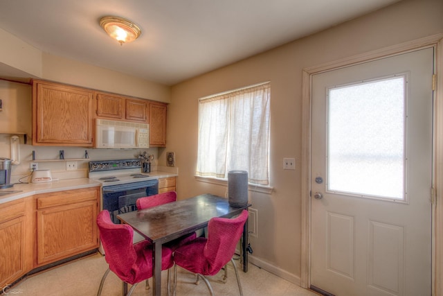 kitchen with white appliances, plenty of natural light, baseboards, and light countertops