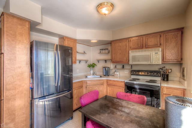 kitchen featuring range with electric cooktop, white microwave, freestanding refrigerator, light countertops, and a sink