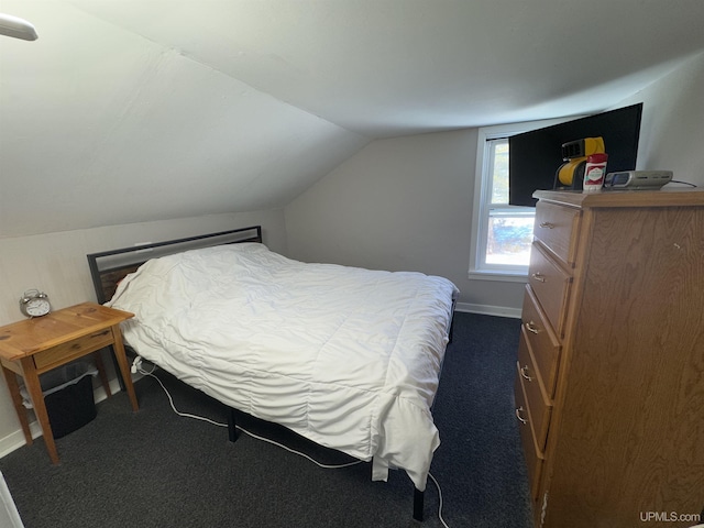 bedroom with vaulted ceiling, dark carpet, and baseboards