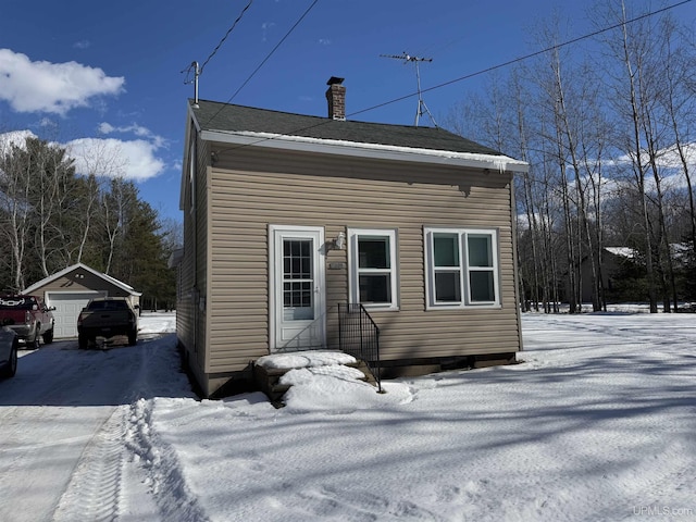 exterior space with a garage, a chimney, and an outdoor structure