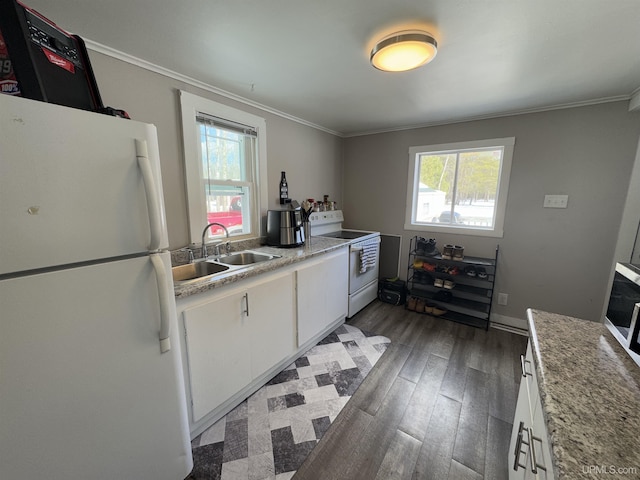 kitchen featuring light countertops, white cabinets, a sink, white appliances, and plenty of natural light