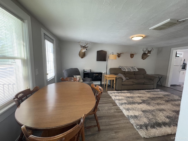 dining room featuring a textured ceiling, visible vents, and wood finished floors