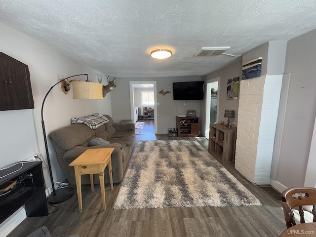 living area featuring dark wood-style floors, visible vents, and a textured ceiling