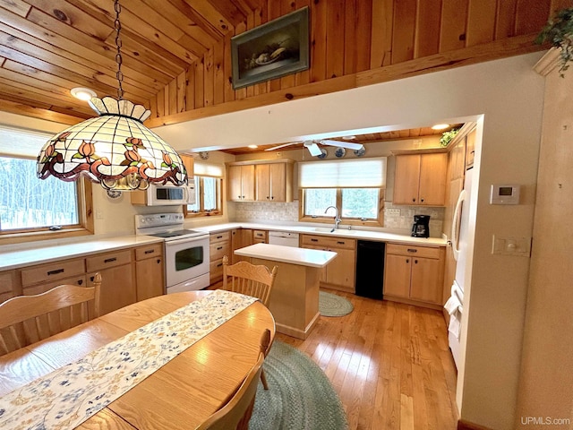 kitchen featuring white appliances, light countertops, light brown cabinetry, tasteful backsplash, and decorative light fixtures