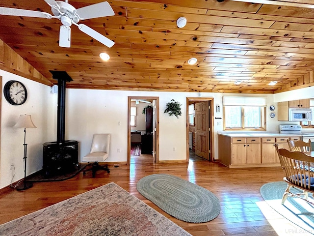 living area with a wood stove, light wood finished floors, and wood ceiling