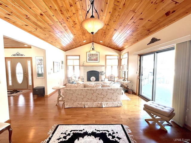 living area featuring baseboards, lofted ceiling, wood ceiling, wood finished floors, and a fireplace