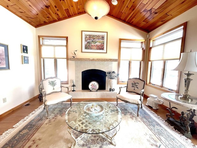 sitting room with lofted ceiling, wooden ceiling, a tiled fireplace, and wood finished floors