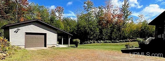 view of yard with a garage, an outbuilding, and driveway