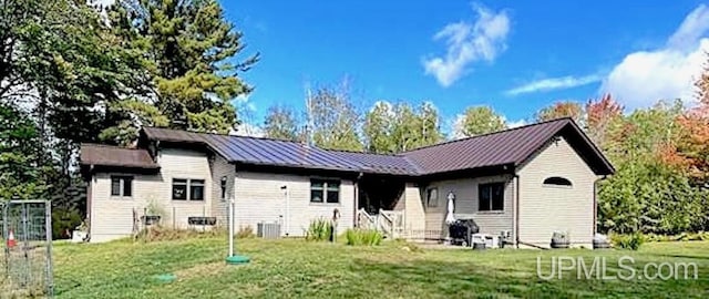 rear view of house with a yard, central air condition unit, entry steps, a standing seam roof, and metal roof