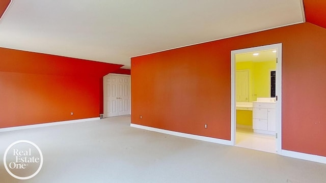 spare room with baseboards, lofted ceiling, and light colored carpet