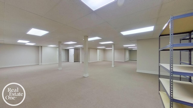 finished basement with light colored carpet, a drop ceiling, and baseboards