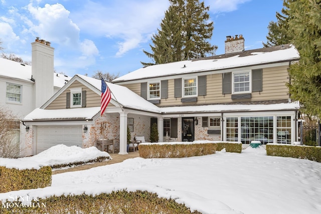 snow covered house with a chimney and an attached garage