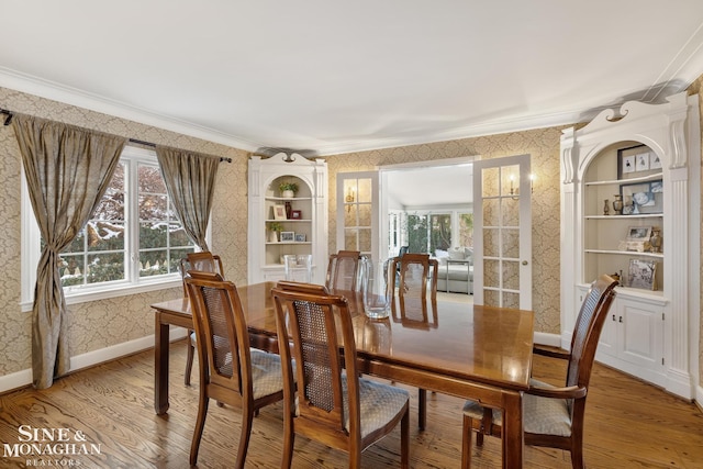 dining room with wallpapered walls, baseboards, wood finished floors, and ornamental molding