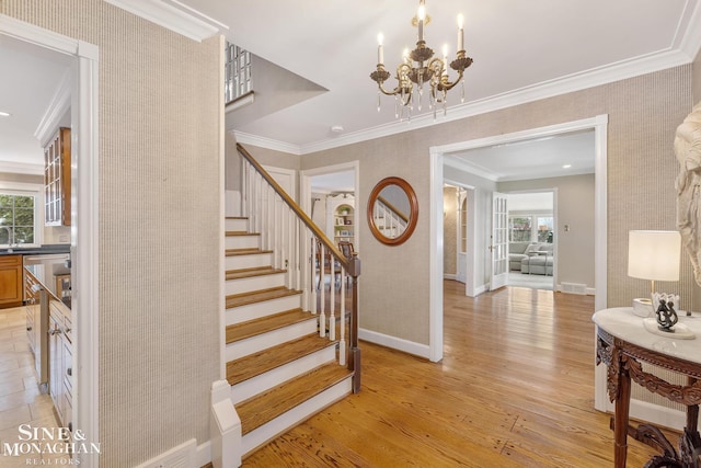 stairs with a chandelier, wood finished floors, visible vents, baseboards, and crown molding