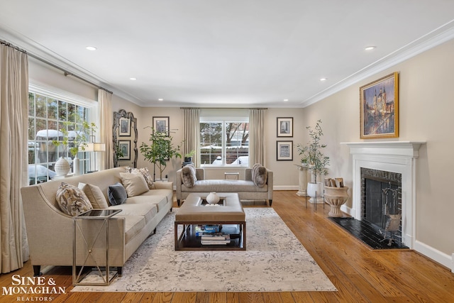 living room featuring a high end fireplace, a healthy amount of sunlight, crown molding, and light wood finished floors