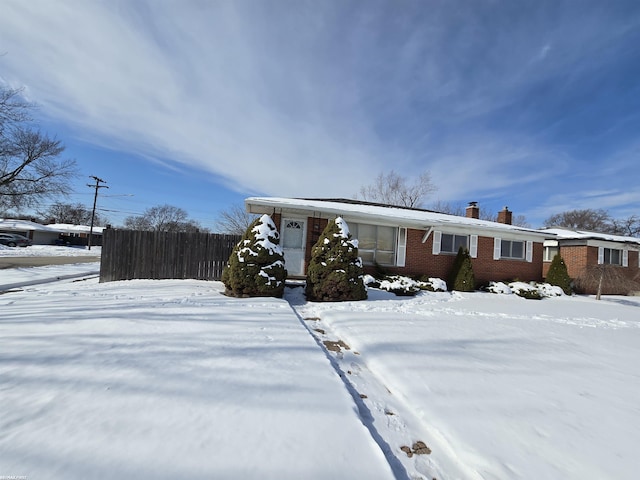 view of front of house with brick siding, fence, and a chimney