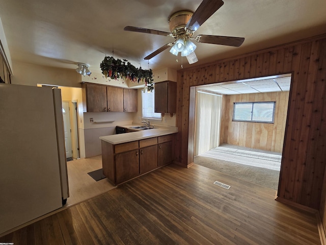 kitchen with visible vents, freestanding refrigerator, a peninsula, light countertops, and a sink