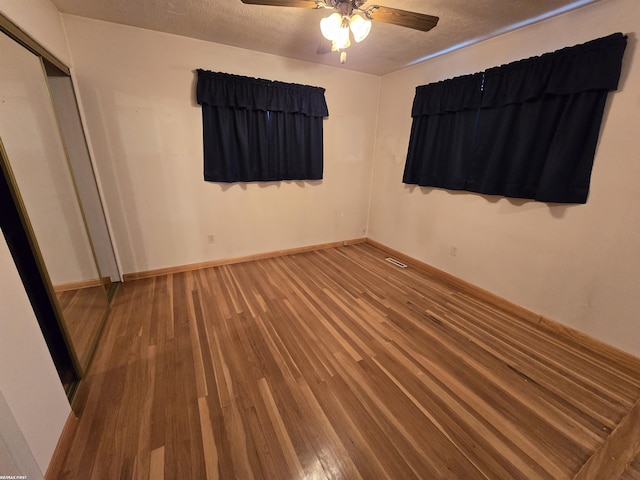 unfurnished bedroom with a textured ceiling, wood finished floors, visible vents, and baseboards