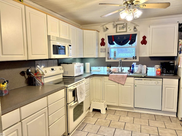 kitchen featuring white appliances, dark countertops, a sink, and white cabinets