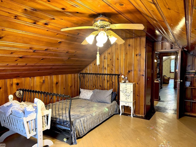 bedroom featuring lofted ceiling, wooden ceiling, wood finished floors, and wooden walls