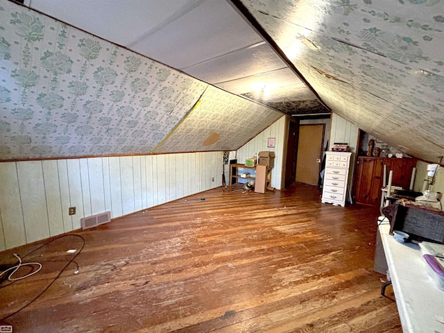 bonus room featuring wood walls, vaulted ceiling, visible vents, and dark wood finished floors