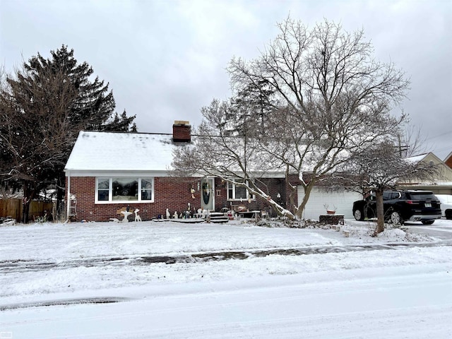 view of front facade with an attached garage, a chimney, and brick siding