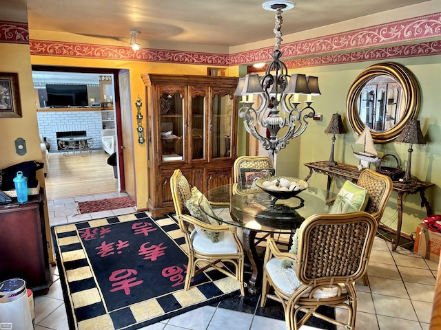 dining room featuring a notable chandelier, a fireplace, and light tile patterned floors