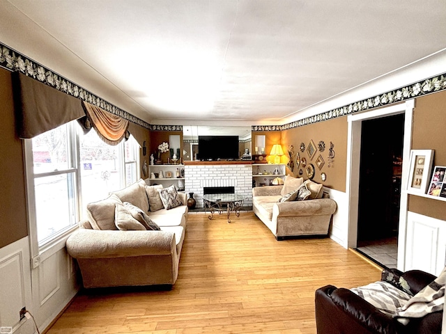 living room featuring wainscoting, light wood finished floors, and a fireplace