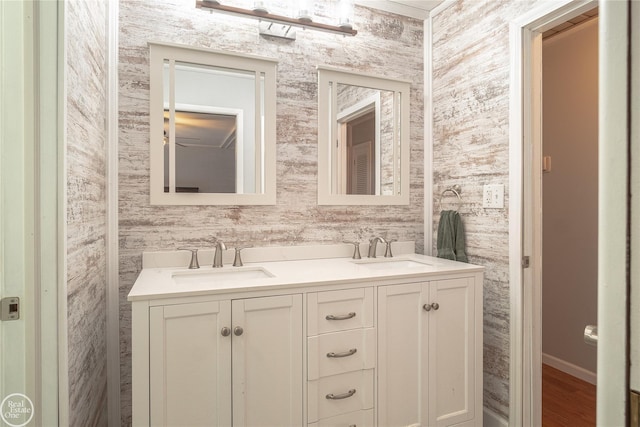 full bath featuring double vanity, a sink, and wallpapered walls