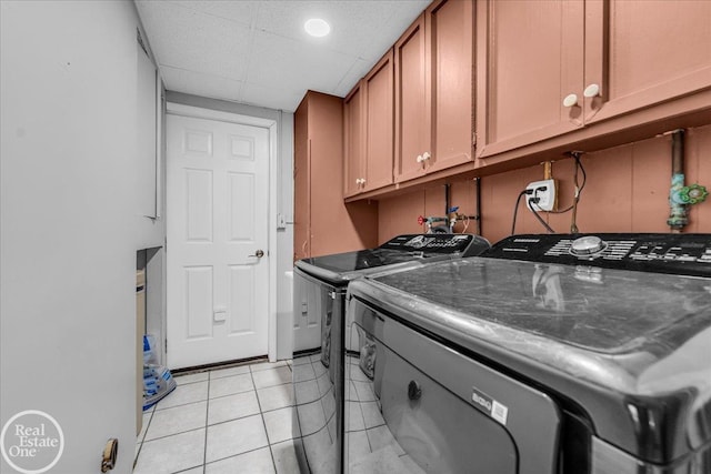 laundry room with cabinet space, washing machine and dryer, and light tile patterned floors