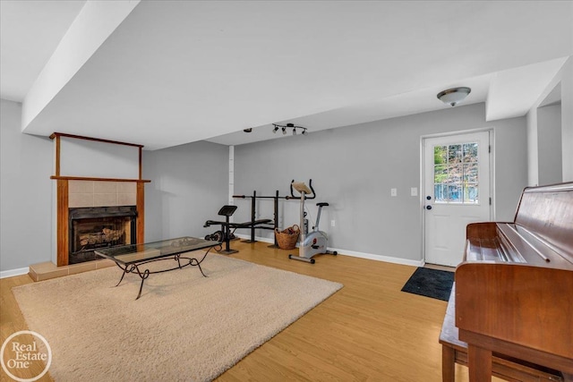 workout room featuring a fireplace, wood finished floors, and baseboards