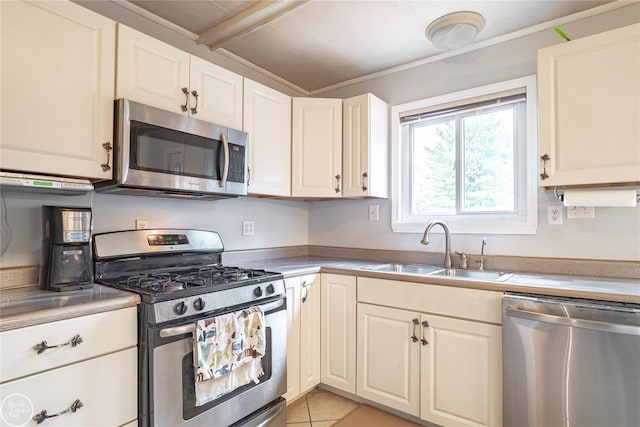 kitchen featuring light tile patterned floors, light countertops, appliances with stainless steel finishes, white cabinetry, and a sink