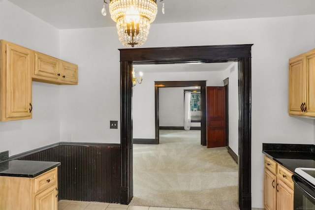 kitchen featuring electric range, light brown cabinets, a notable chandelier, and light colored carpet