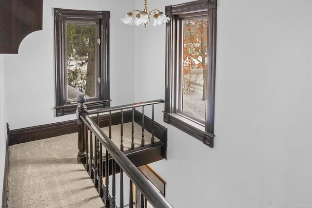 stairs featuring carpet flooring, a notable chandelier, and baseboards