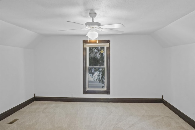 additional living space with light carpet, lofted ceiling, visible vents, and baseboards