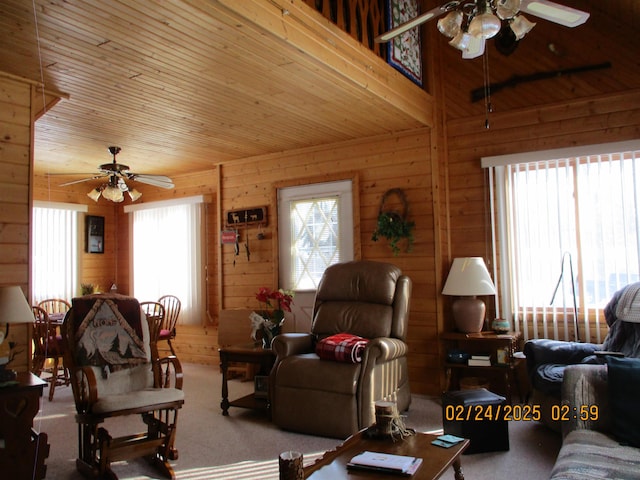 living area with carpet, ceiling fan, wood walls, and wooden ceiling