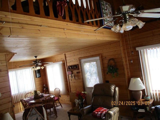 dining area with ceiling fan, wood walls, and plenty of natural light