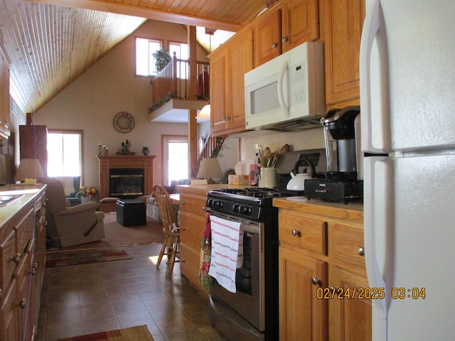 kitchen featuring white appliances, a glass covered fireplace, brown cabinets, open floor plan, and light countertops