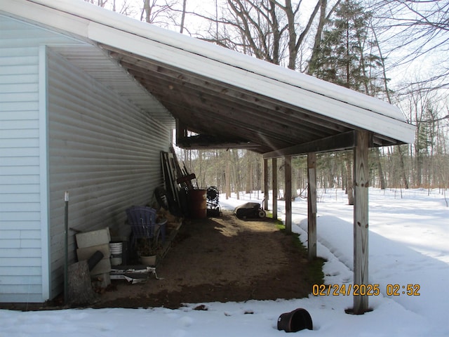 snow covered parking area with an attached carport