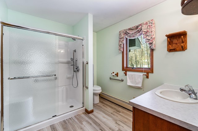 full bathroom with toilet, a baseboard heating unit, wood finished floors, vanity, and a shower stall