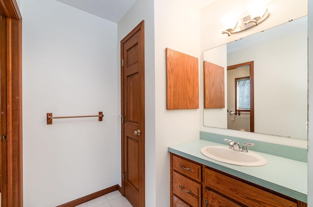 bathroom featuring baseboards, a textured ceiling, and vanity