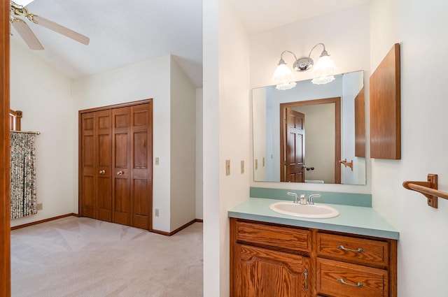 bathroom featuring baseboards, vaulted ceiling, a ceiling fan, and vanity