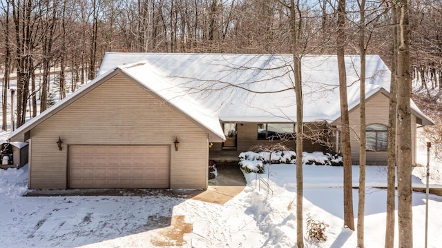 snow covered property with a detached garage