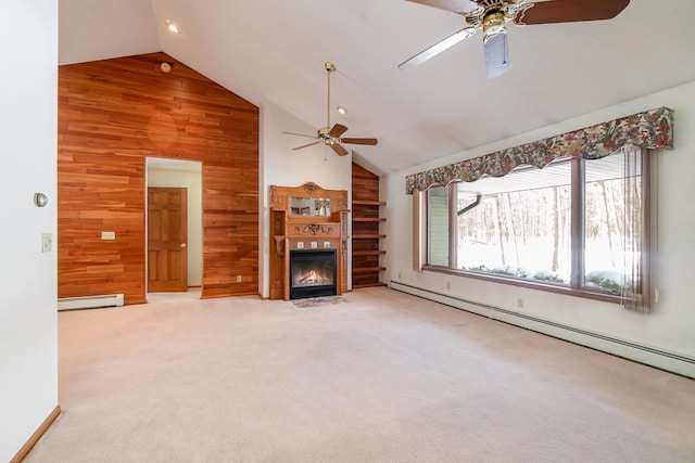 unfurnished living room with wood walls, light colored carpet, baseboard heating, and a glass covered fireplace